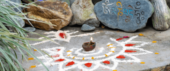 A rangoli laid out with stones and a lamp