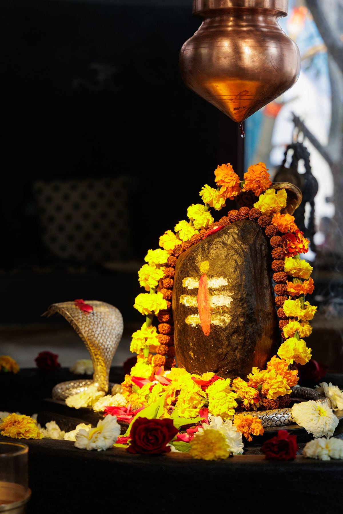 The Swayambhu Shivalinga garlanded in marigolds, lamps lit before it and a copper kalash above
