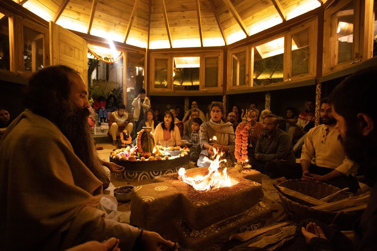 Gurudev Sri Anish at the Yajna fire at night, the Swayambhu garlanded beside it and the Sangha seated around